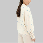 Woman wearing a cream blouse with blue star patterns on a white background